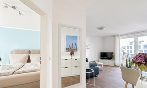 Een moderne woonkamer met een bank, een televisie, een eettafel en een groot raam.