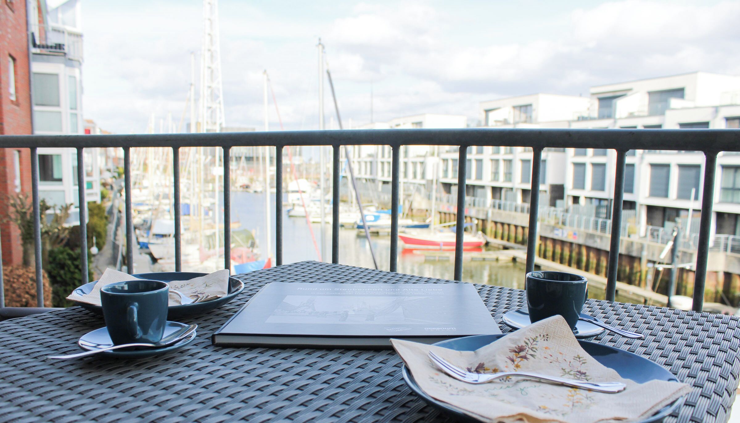 Een balkon met een tafel voor twee, een boek en een menukaart.