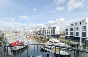 Un port de plaisance avec des bateaux amarrés, des bâtiments modernes et un ciel dégagé.