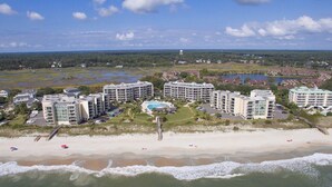 Un hotel costero con varias construcciones, una playa y una torre de agua al fondo.