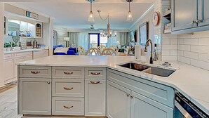 Una cocina moderna con una isla central, armarios blancos e iluminación colgante.