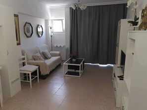 A living room with a sofa, a coffee table, a TV, and a window with curtains. - A charming refuge in San Telmo (Puerto de la Cruz)