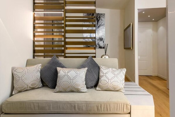 A modern bedroom with a sofa bed, patterned pillows, a wall-mounted light, and a framed picture. - Gian Giacomo Mora Raffinato monolocale (Milan)