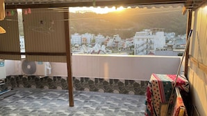 A covered outdoor area with a tiled floor, a table with a colorful tablecloth, and a view of buildings in the background. - Sunny Hotel Vung Tau (Ho Chi Minh City)