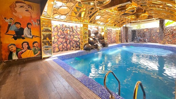 Une piscine intérieure avec un mur en pierre et une fresque murale.