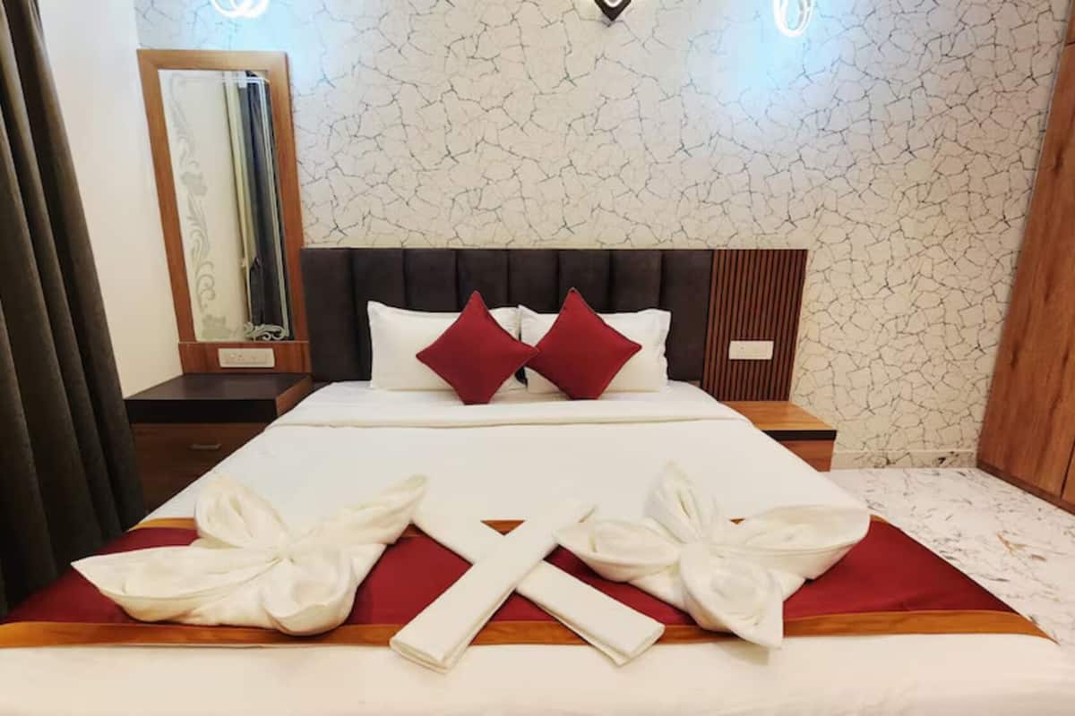 A hotel room with a bed, a nightstand, a mirror, and a wardrobe.