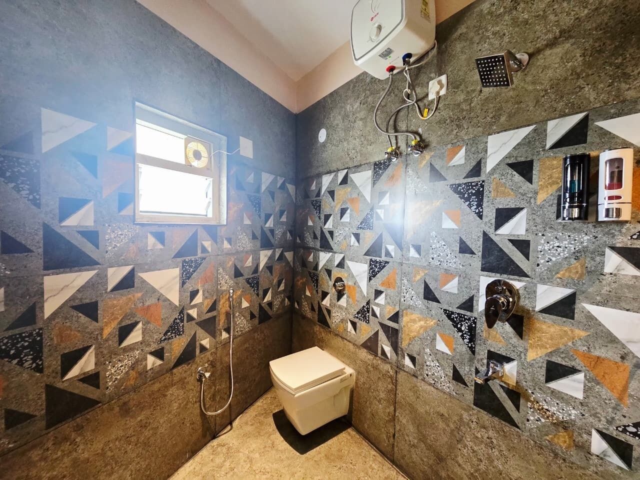 A bathroom with a geometric tile pattern, a toilet, a shower, and a window.