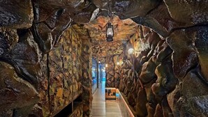 Un couloir étroit aux murs de pierre, doté d’un plancher en bois et illuminé par des lanternes suspendues.