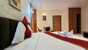 Une chambre d’hôtel avec un grand lit, un bureau, une chaise et une armoire.