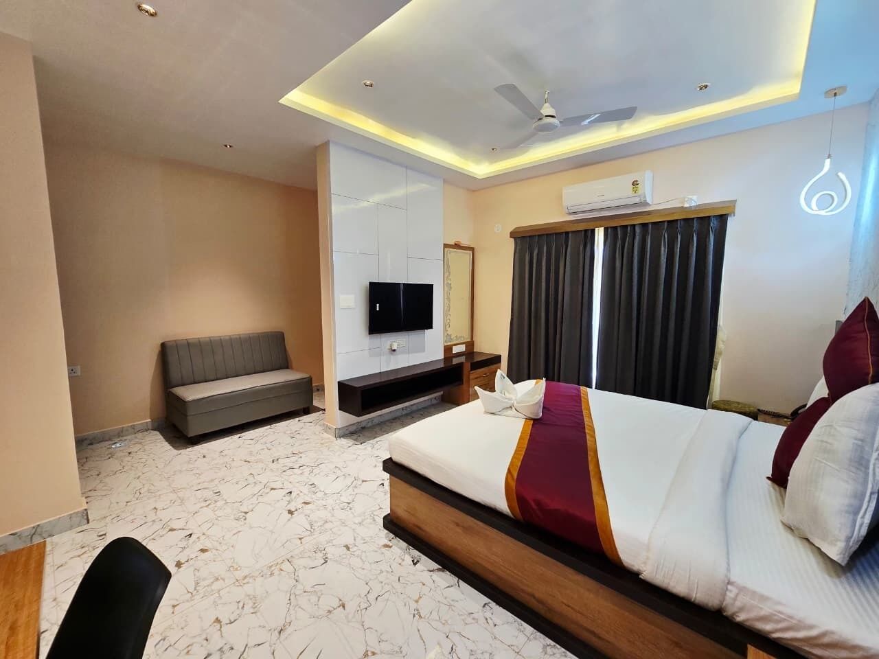 Une chambre d’hôtel équipée d’un lit, d’un canapé, d’une télévision et d’un ventilateur de plafond.