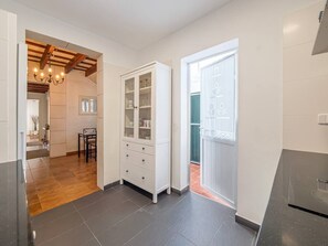 A modern kitchen with a built-in oven, a white cabinet with glass doors, and a dining area with a wooden table and chairs. - Casa Major by 3 Villas Menorca (Fornells)