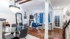 Una sala de estar moderna con una mesa de comedor de vidrio, sillones azules, un sofá gris y una escalera de madera.