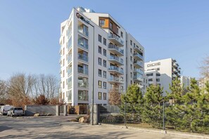 A multi-story residential building with balconies, a gated entrance, and a parking area. - Spacious Apartment | Two Bedrooms and Air Conditioning (Warszawa)