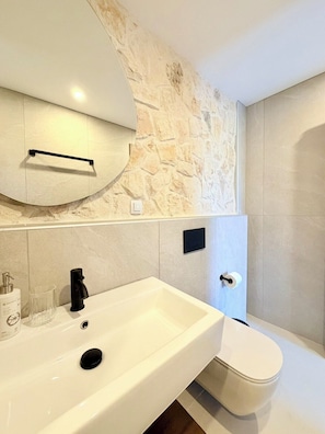Un baño con un lavamanos blanco, grifo negro y un inodoro.