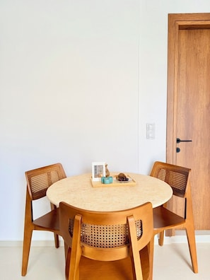 Una mesa redonda de madera con dos sillas, una puerta y un interruptor de luz en la pared.