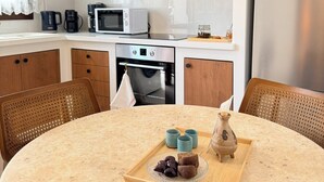 Eine moderne Küche mit Holzsärchen, einer Mikrowelle, einem Backofen und einer Essecke mit einem runden Tisch.