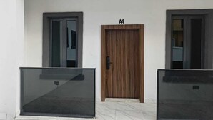 A building with two doors, a wooden door labeled 'A4' and a glass door, each with a small rectangular object on the floor. - Jasmine Chidera Apartments (Lagos)