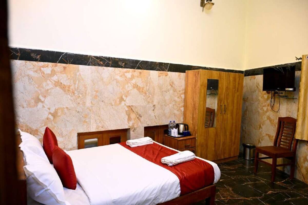 Una camera d'albergo con un letto, un armadio in legno, una televisione e una sedia.