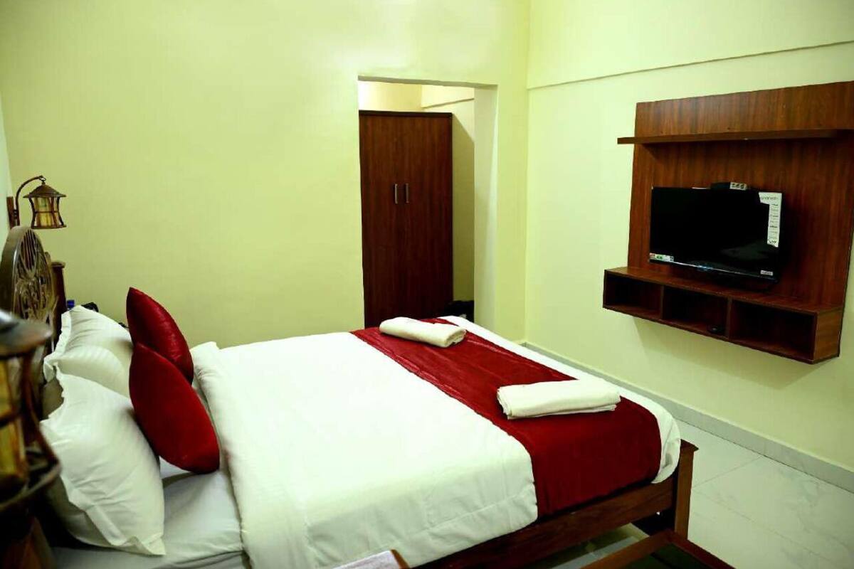 Una camera d'albergo con un letto, un armadio, una televisione e una lampada.