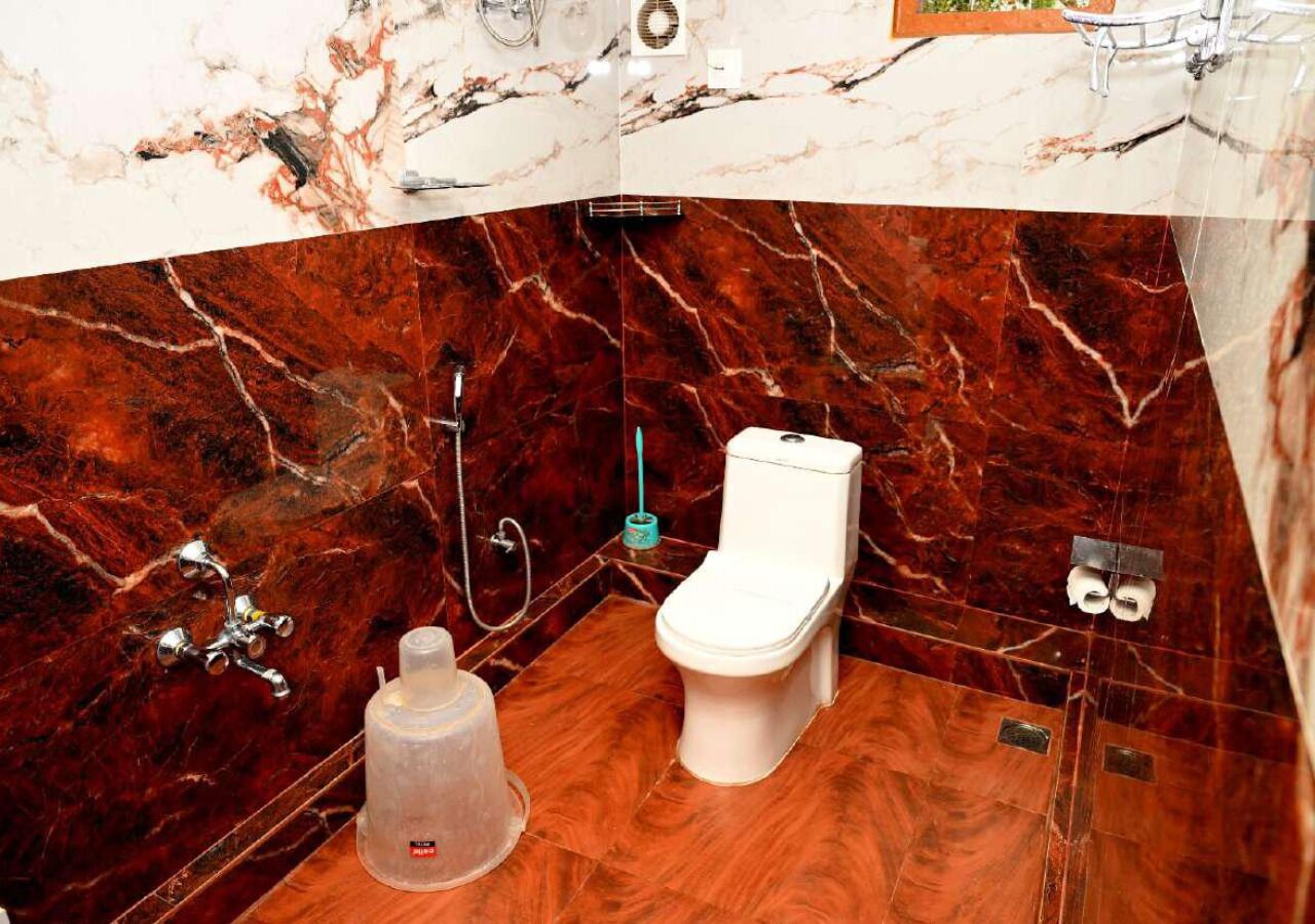 A bathroom with a marble vanity, a toilet, and a large water dispenser.