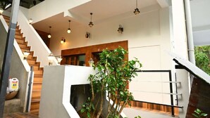 Un interior moderno con una escalera, detalles de madera e iluminación colgante.