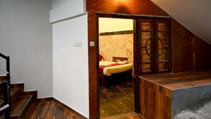 Un dormitorio con cama, un banco de madera y un baño pequeño con inodoro y lavamanos.