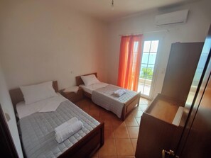 A room with two beds, a wardrobe, and a window with curtains.