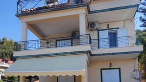 Un edificio a due piani con un balcone, posti a sedere all'aperto e un'antenna parabolica.