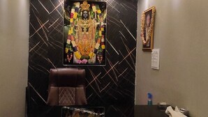 A reception area with a marble wall, a reception desk, a brown chair, a blue sofa, and a framed picture on the wall. - Hotel Taarini Rajwada Indore By LOTO (Indore)