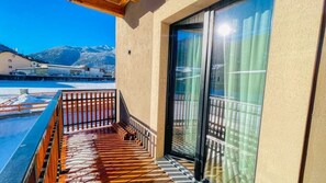 A balcony with a wooden floor, a glass door, and a view of a snowy landscape. - Appartamento Valley Lodge - Affitti Brevi Italia (Oulx)