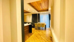 A modern room with a wooden ceiling, a dining area with chairs and a table, and a sofa. - Appartamento Valley Lodge - Affitti Brevi Italia (Oulx)