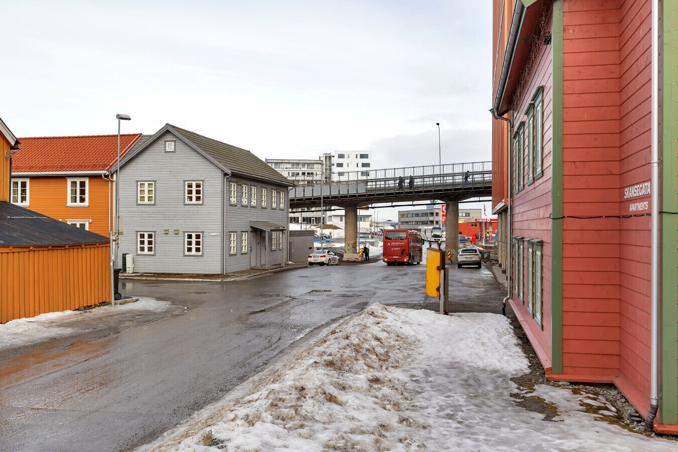 Una calle con edificios, un puente peatonal y vehículos.