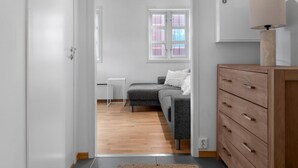 A modern, well-lit room with a grey sofa, wooden dresser, and a small table.