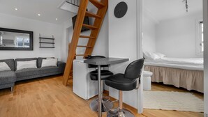 A modern living space with a loft bedroom, a dining area, and a kitchen.