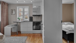 A compact kitchen with modern appliances, a dining area, and a bedroom with a bed.
