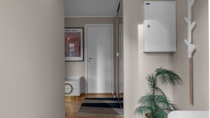 A hallway with a dark tiled floor, a white door, a framed picture, a white cabinet, and a potted plant.