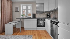 A modern kitchen with white cabinets, stainless steel appliances, a built-in oven, and a coffee maker.