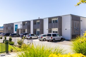 A modern building with multiple floors, a parking lot with several cars, and a sign indicating 'HARABRUCK APARTMENTS.' - Harabruck Apartments (Gmünd)