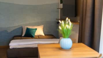 A cozy room with a sofa, pillows, a small table, and a TV mounted on the wall.