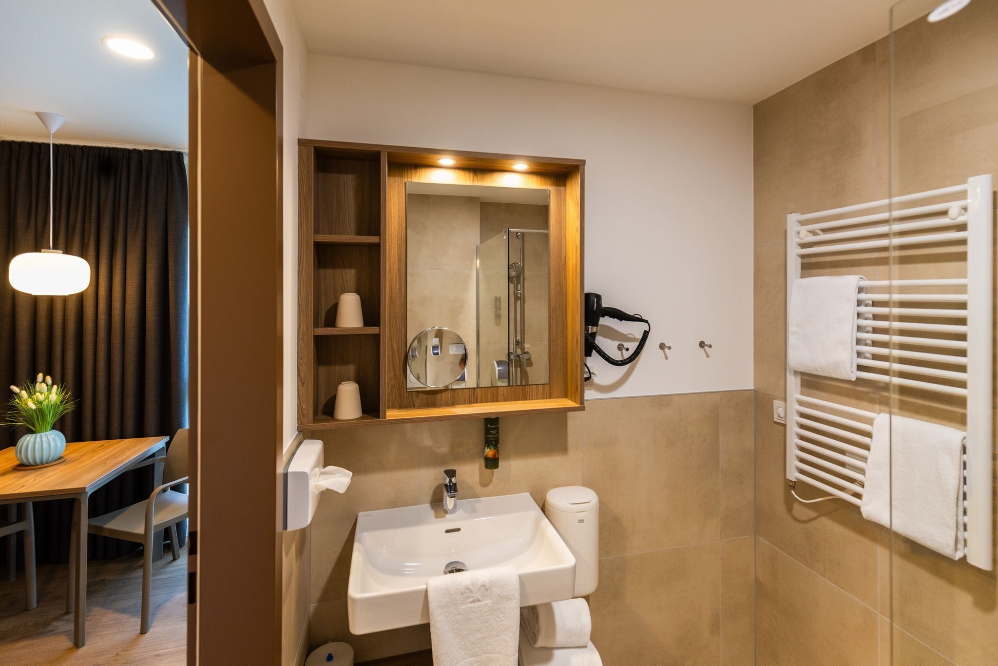 A modern bathroom with a sink, mirror, towel rack, and shower.