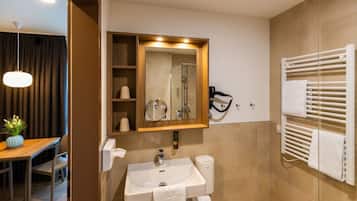 A modern bathroom with a sink, mirror, towel rack, and shower.