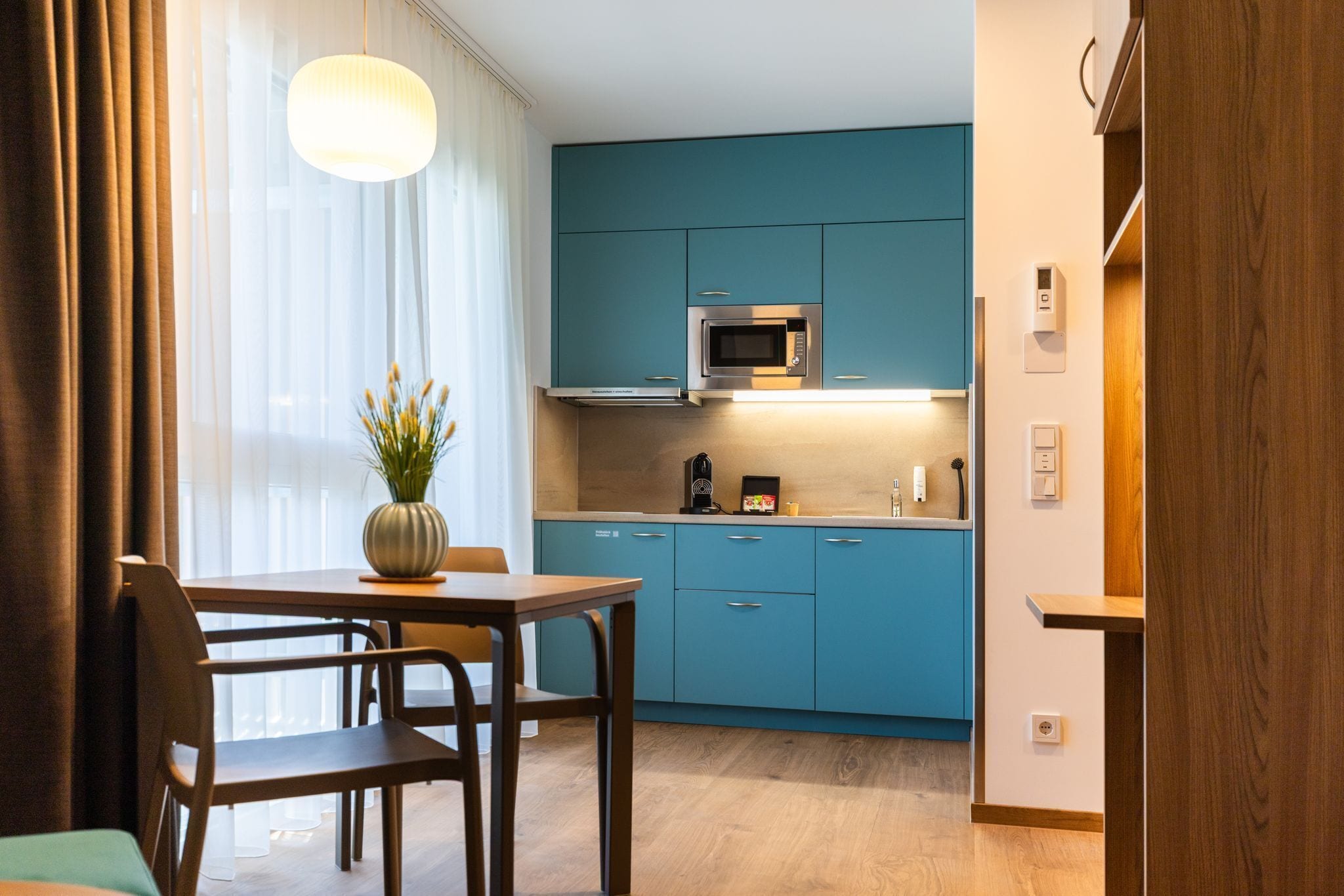 Una cocina moderna con armarios azul turquesa, un microondas y una cafetera.