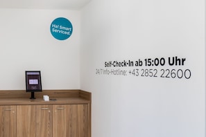 Een zelf incheck automaat en een bord dat aangeeft dat zelf inchecken mogelijk is om 15:00 Uhr, met een 24/7 informatie telefoonnummer.