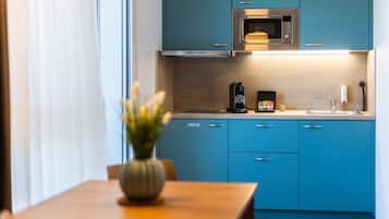 Eine moderne Küche mit blauen Schränken, einer Mikrowelle, einer Kaffeemaschine und einem Blumenstrauß auf dem Tisch.