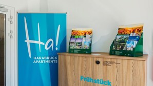 A blue sign with 'Ha! HARABRUCK APARTMENTS' and a wooden cabinet with brochures and a sign.