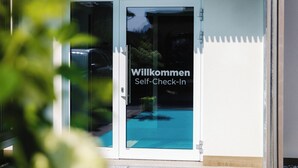 A glass door with a welcome sign and a pool view.