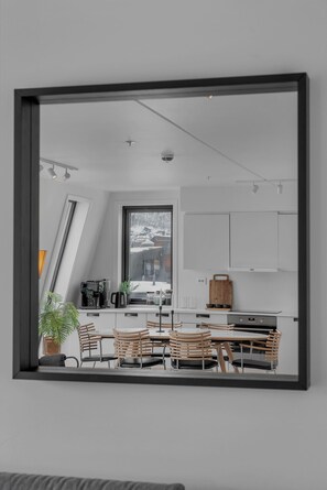 A modern kitchen with white cabinets, a large window, and a dining area with wooden chairs and a table.
