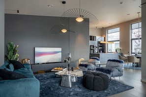 Una sala de estar moderna con sofá, reposapiés, mesa de centro y una obra de arte en la pared.
