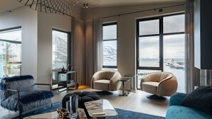 A modern living room with large windows, a sofa, a chair, and a coffee table. - Northstay - Polar Night I Exclusive Arctic Penthouse (Tromsø)