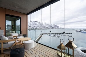 Un balcón con vista al puerto, muebles de madera y dos faroles.